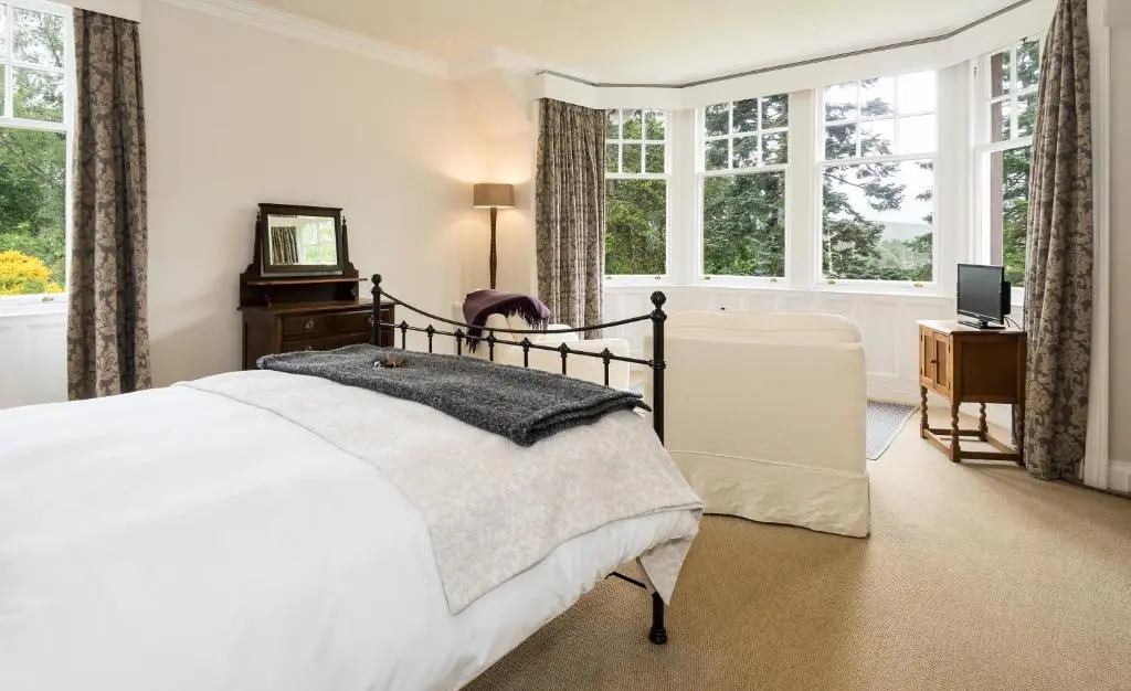 a white bedroom with a bed and windows at Coig na Shee Guest House in Newtonmore