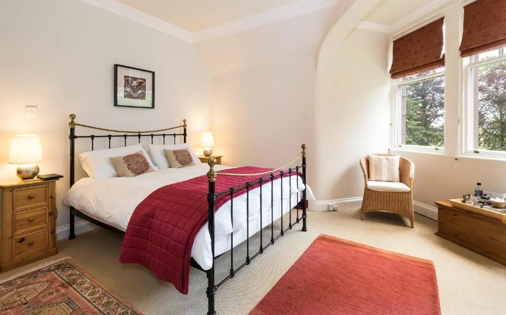 a bedroom with a bed with a red blanket at Coig na Shee Guest House in Newtonmore