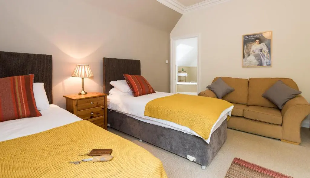 a bedroom with two beds and a couch at Coig na Shee Guest House in Newtonmore