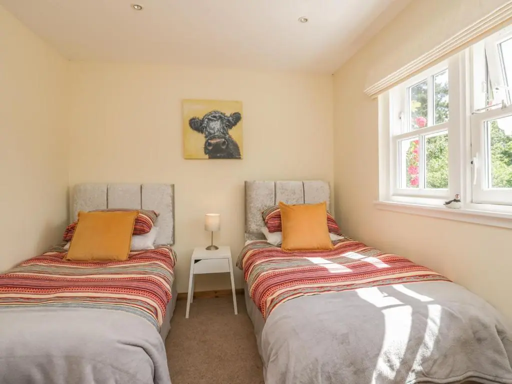 two beds in a room with two windows at Drumhead Bothy in Banchory