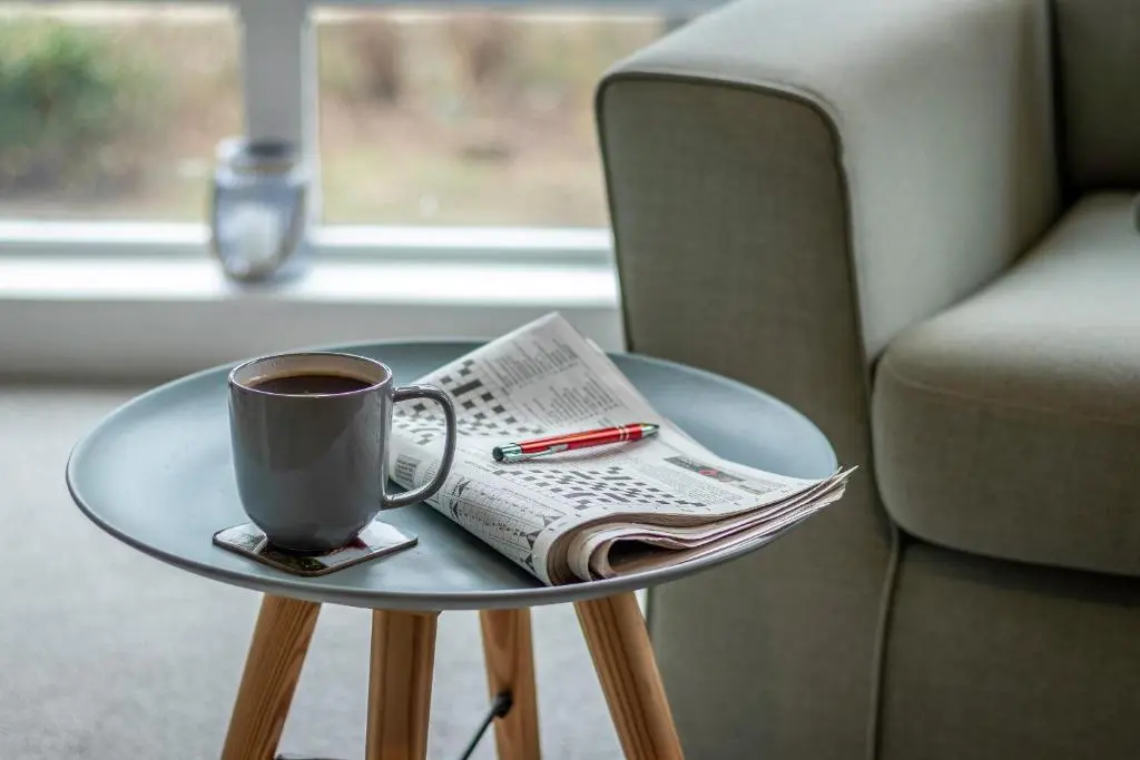 a cup of coffee and a newspaper on a glass table at Fishertown House in Nairn