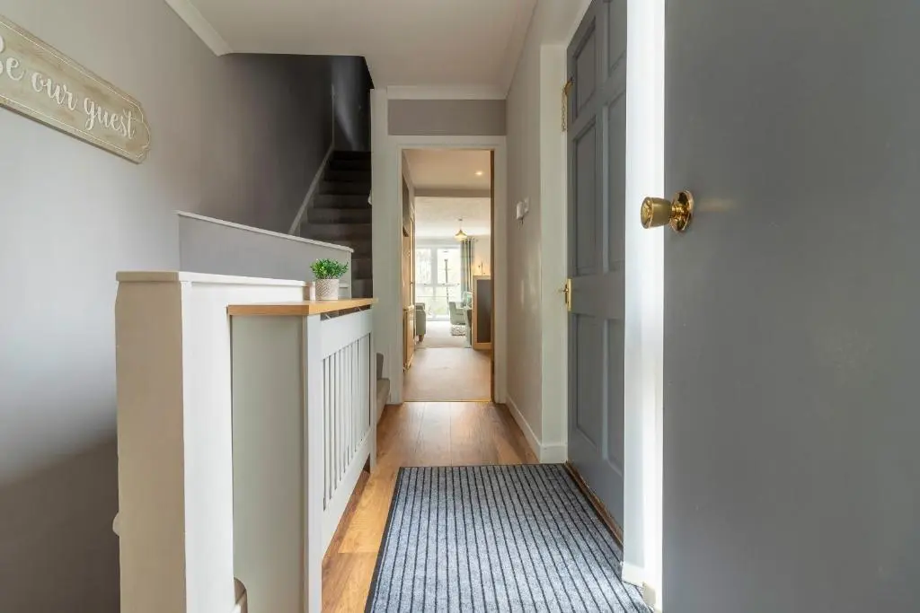 a hallway with a white door and a blue rug at Fishertown House in Nairn