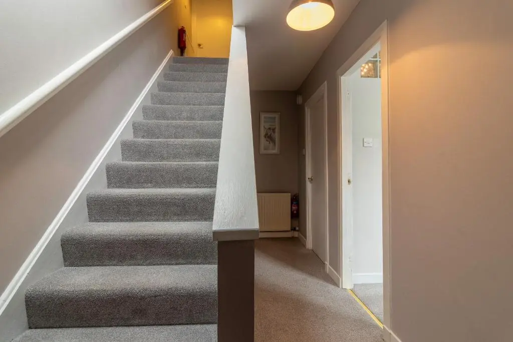 a staircase in a home with grey carpeting and a white wall at Fishertown House in Nairn