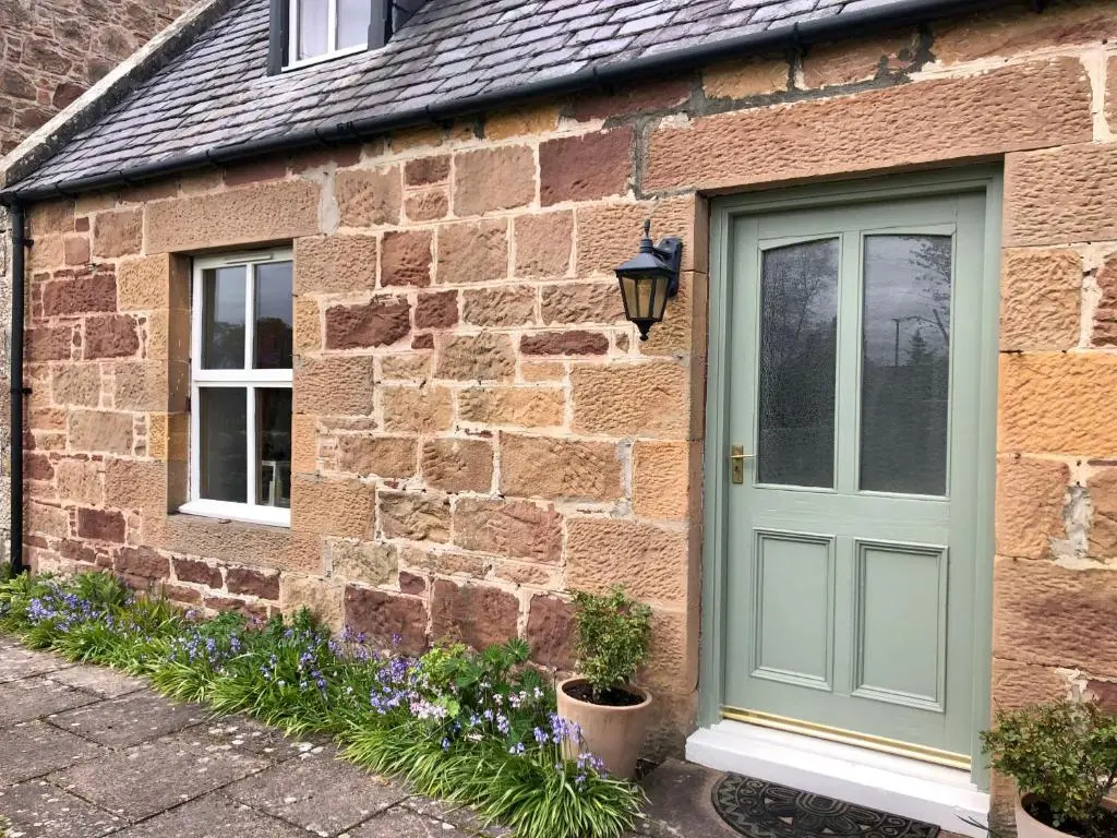 a brick house with a green door and two windows at Glenmuir Cottage in Dornoch