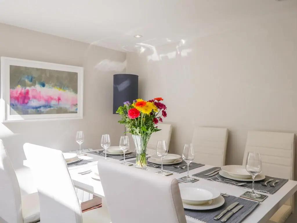 a dining room with a table with a vase of flowers at 36 Sandend Village in Banff