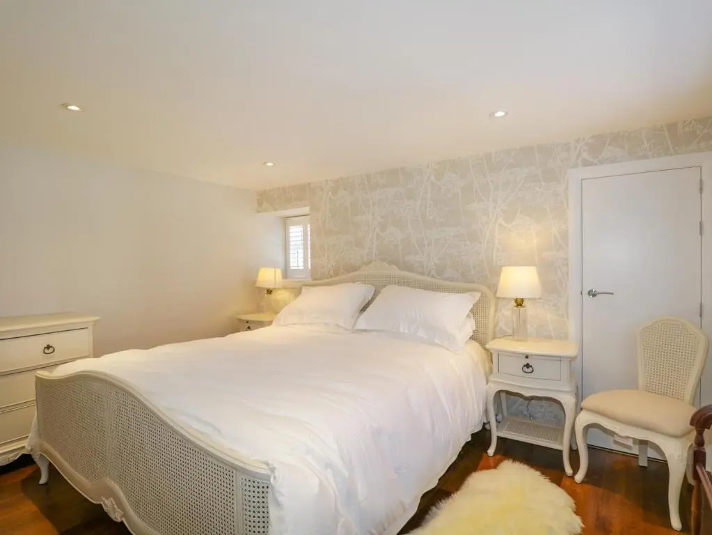 a bedroom with a large white bed and a chair at 36 Sandend Village in Banff