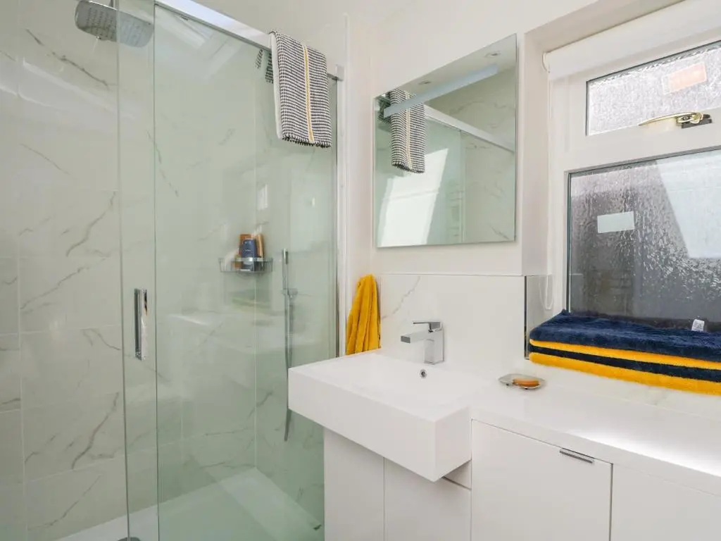 a white bathroom with a sink and a shower at 36 Sandend Village in Banff