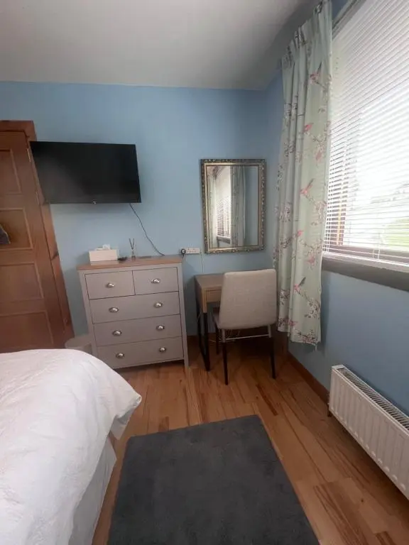 a bedroom with a bed and a desk and a window at Black Isle View in Dingwall