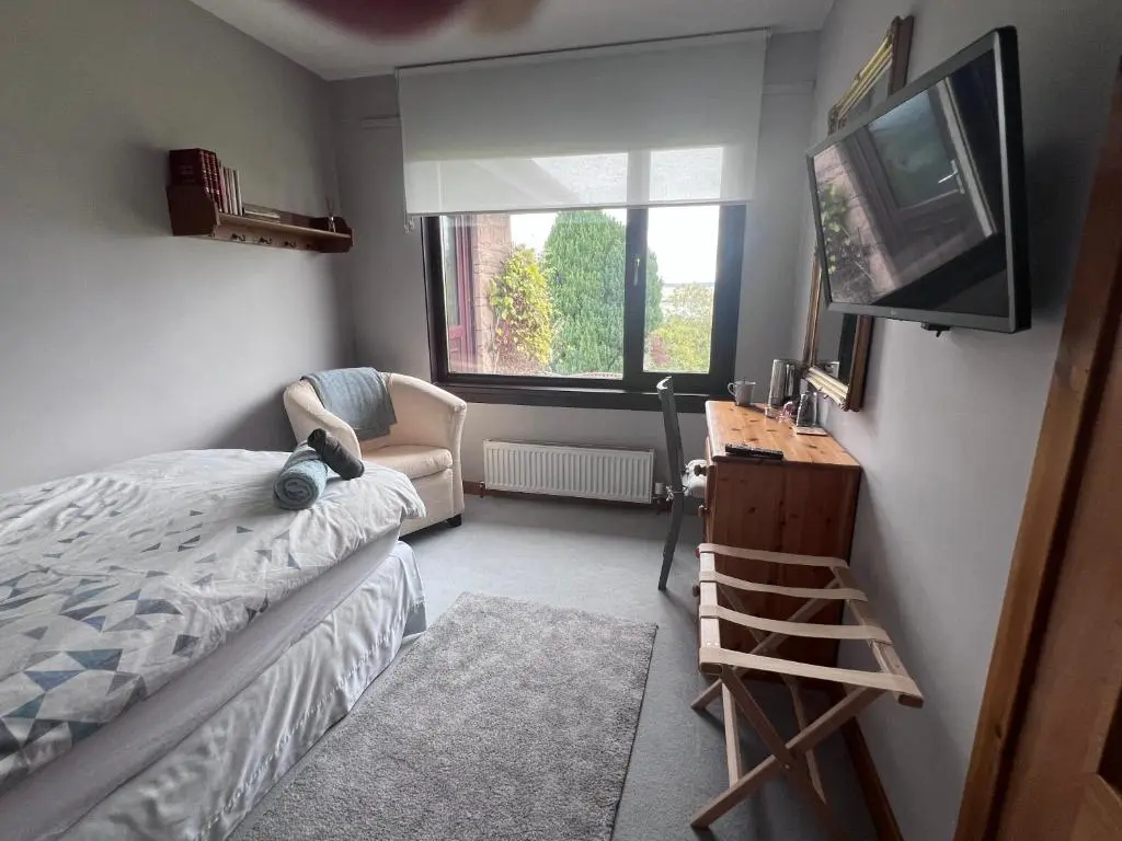 a bedroom with a bed and a television and a chair at Black Isle View in Dingwall