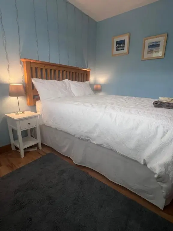 a bedroom with a large white bed and a night stand at Black Isle View in Dingwall