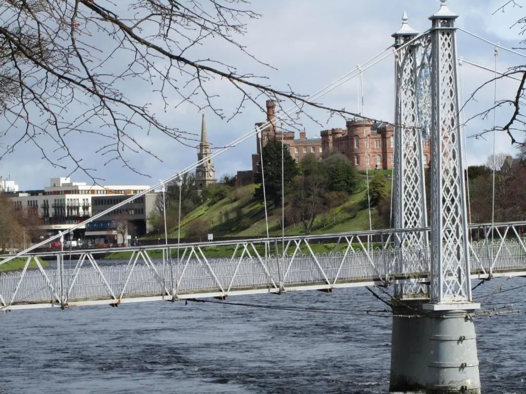 a bridge over a river with buildings in the background at River Walk Inverness in Inverness
