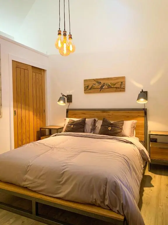 a bedroom with a large bed with a wooden headboard at Balloan Cottage Cowshed in Inverness