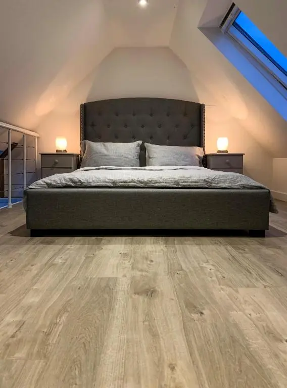 a bedroom with a bed and wooden flooring at Balloan Cottage Cowshed in Inverness