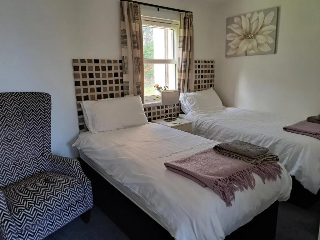 two beds in a room with a chair and a window at Inchmarlo Golf Resort, Banchory Villa 26 AS 00266F in Banchory