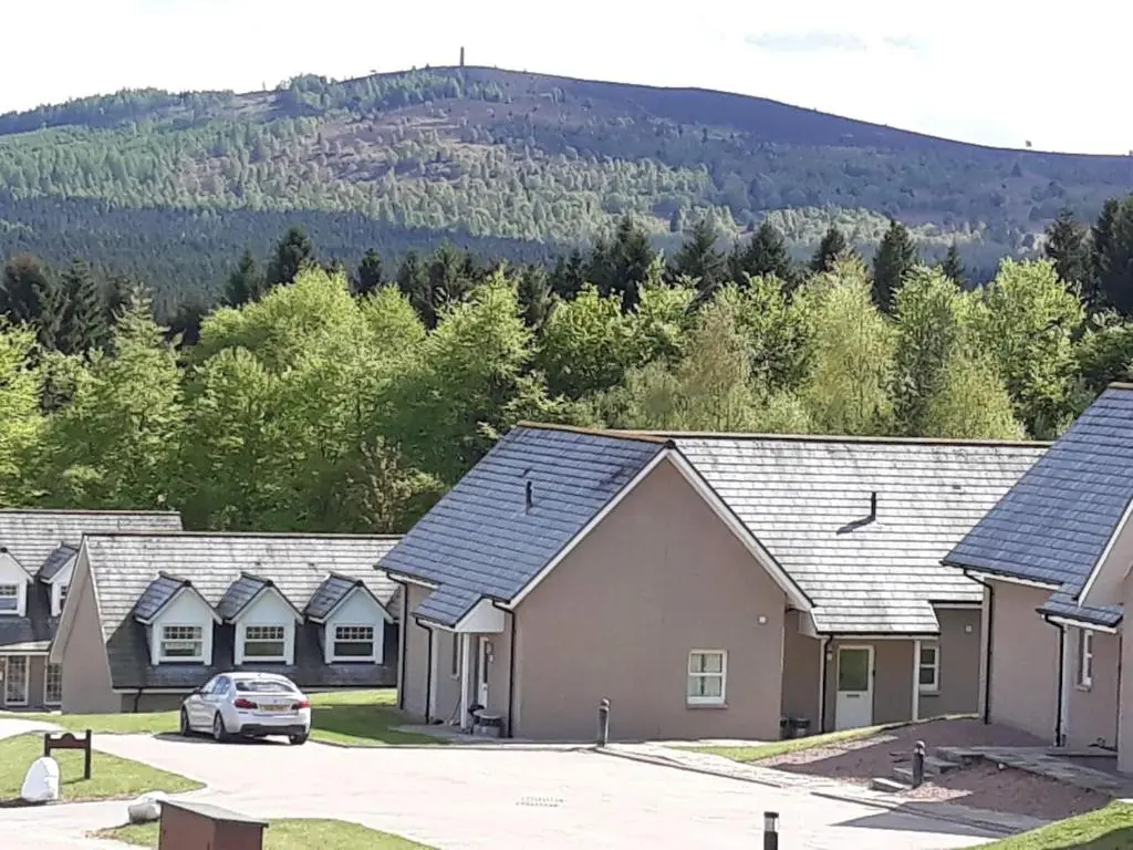a row of houses with a car parked in a parking lot at Inchmarlo Golf Resort, Banchory Villa 26 AS 00266F in Banchory