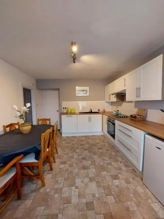 a kitchen with a table and chairs and a kitchen with white cabinets at Mortlach Cottage in Dufftown