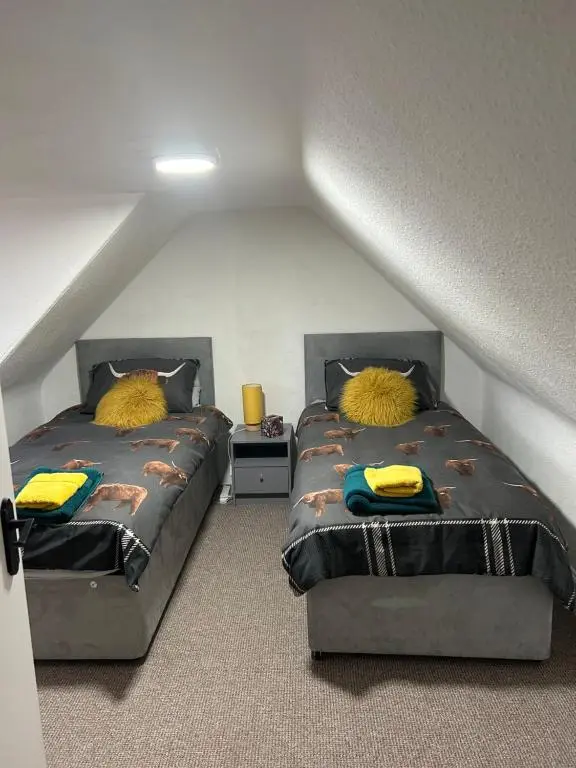 a attic bedroom with two beds with yellow pillows at Mortlach Cottage in Dufftown