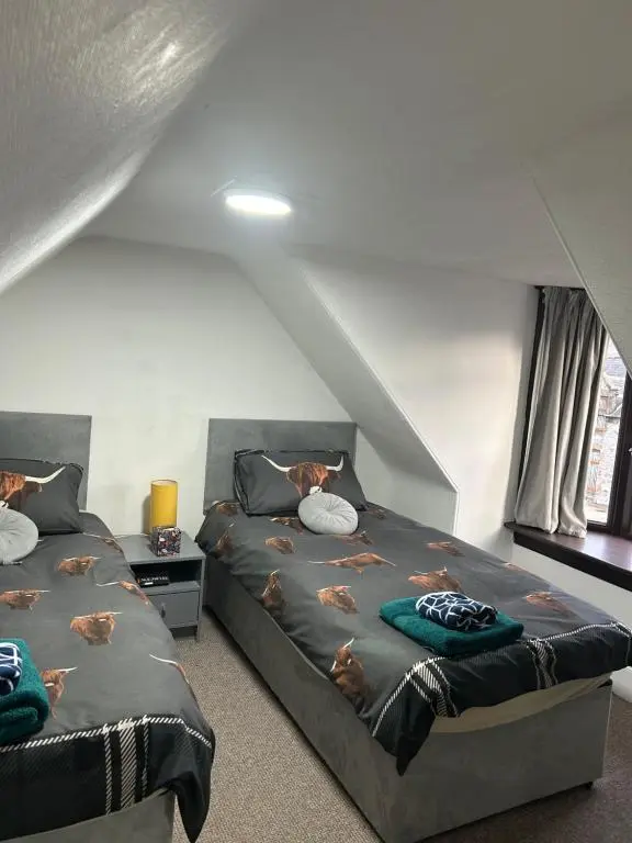 a attic bedroom with two beds and a window at Mortlach Cottage in Dufftown