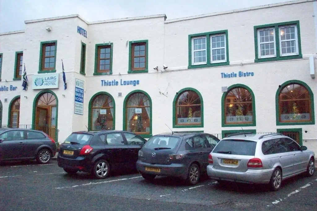 three cars parked in a parking lot in front of a building at Lairg Highland Hotel in Lairg