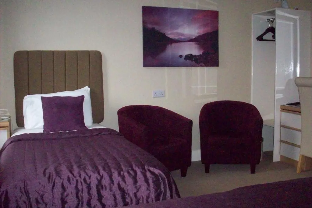 a bedroom with a bed and a chair at Lairg Highland Hotel in Lairg