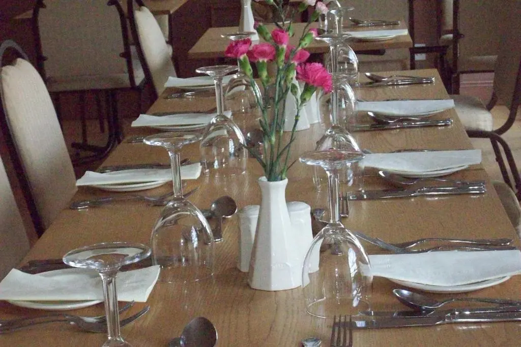 a table with glasses and flowers in a white vase at Lairg Highland Hotel in Lairg