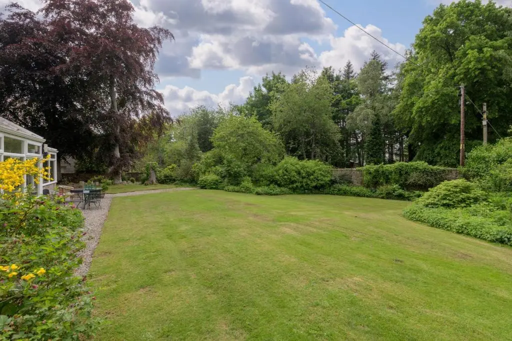 a yard with a large lawn with trees and bushes at The Cabin at No 45 in Ballater