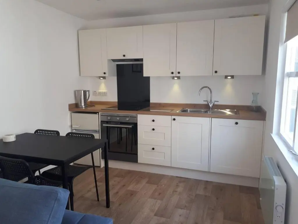 a kitchen with white cabinets and a table and a sink at The Cabin at No 45 in Ballater