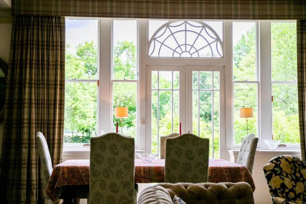 a dining room with two tables and a large window at Scatwell House in Garve