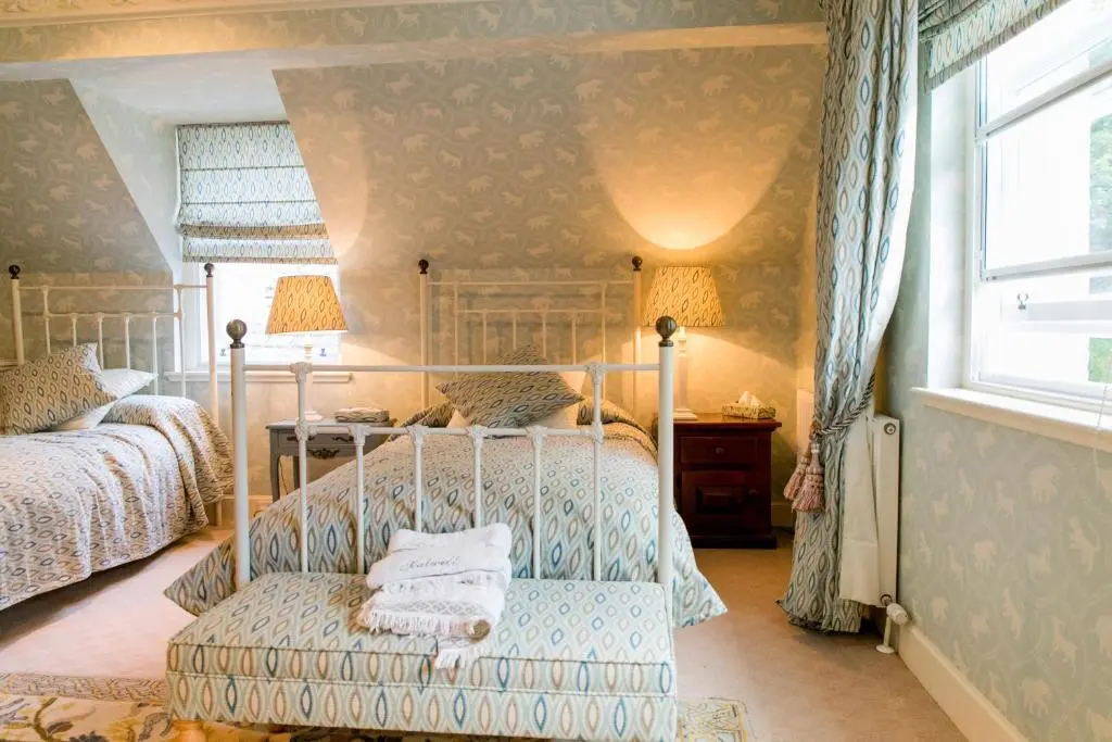 a bedroom with two beds and a chair and a window at Scatwell House in Garve