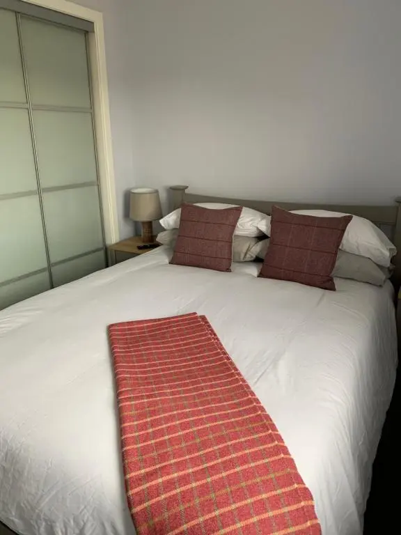 a bed with a red rug on top of it at 23 C Allan Gardens in Dornoch