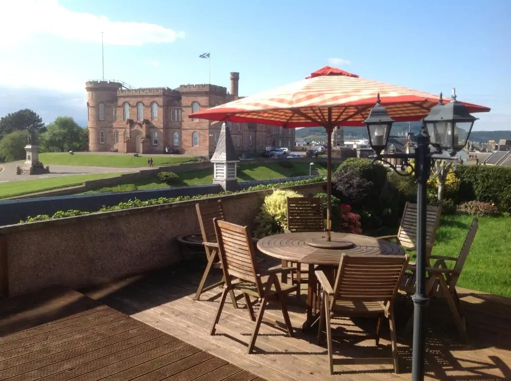 a patio with a table and chairs and an umbrella at Ardentorrie Guest House in Inverness