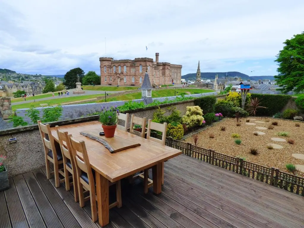 a wooden table and chairs on a deck with a castle at Ardentorrie Guest House in Inverness