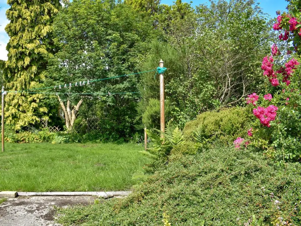 a garden with pink flowers and a pole at Spey Cottage in Aberlour
