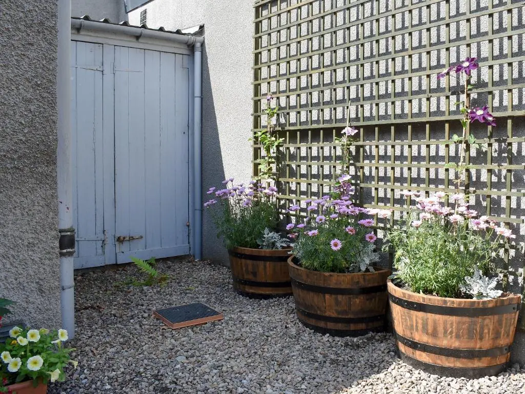 three potted plants in barrels next to a building at Spey Cottage in Aberlour