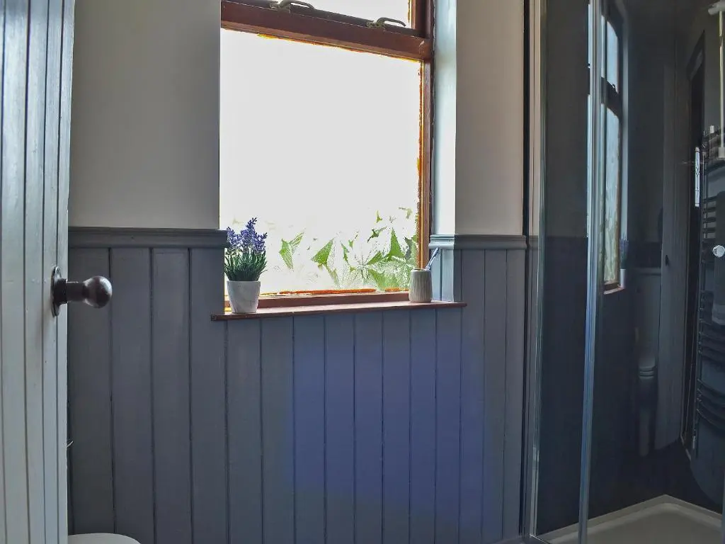 a bathroom with a window and a blue wall at Mains Of Auchmedden Cottage in Pennan
