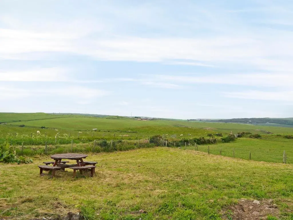 a picnic table in the middle of a field at Mains Of Auchmedden Cottage in Pennan