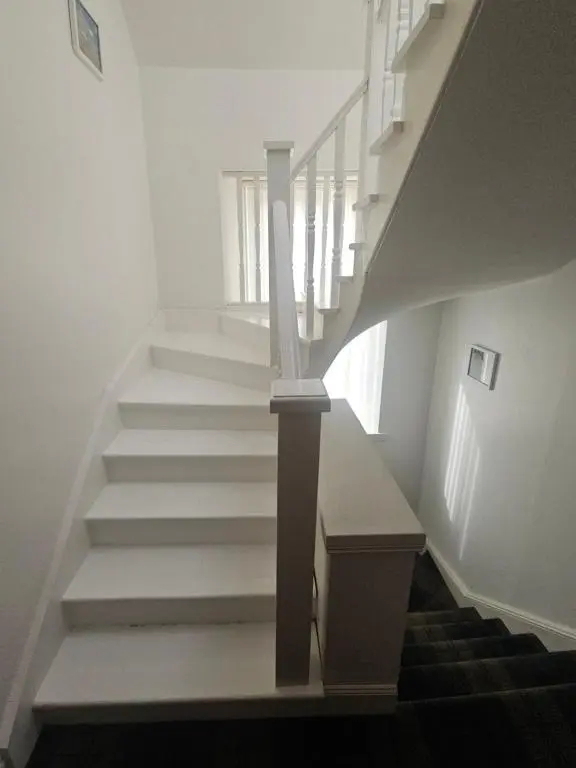 a staircase in a house with white walls at Telford Road Apartment in Inverness