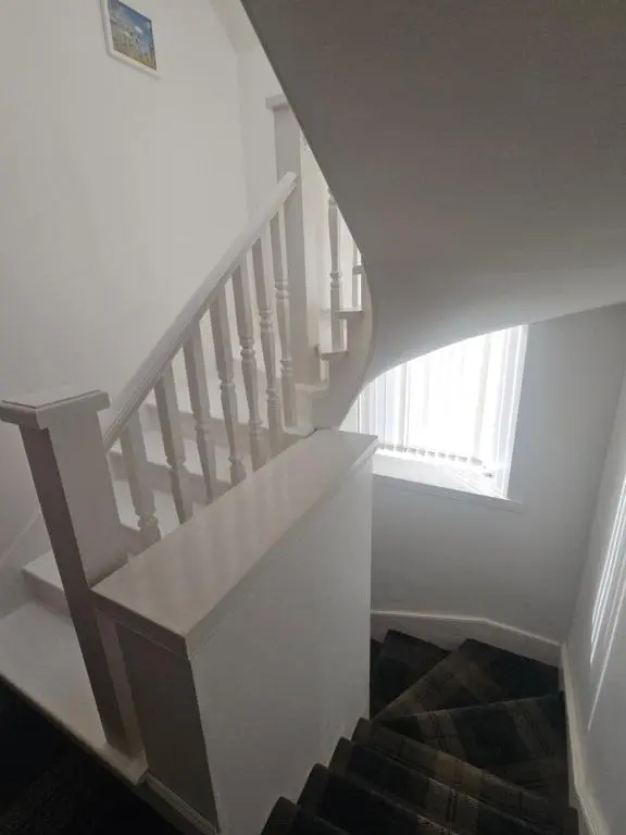 a stairway with a white stair case and a window at Telford Road Apartment in Inverness