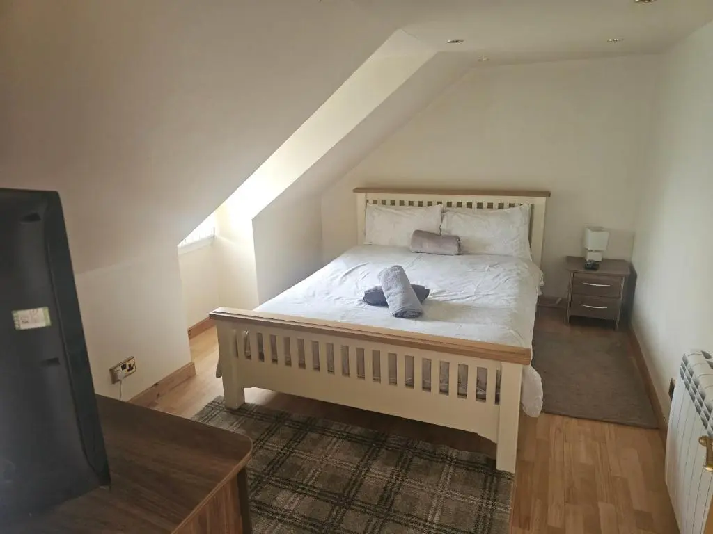 a bedroom with a bed in a attic with a tv at Telford Road Apartment in Inverness