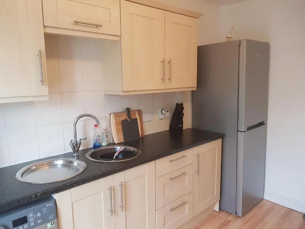 a kitchen with a sink and a refrigerator at Telford Road Apartment in Inverness