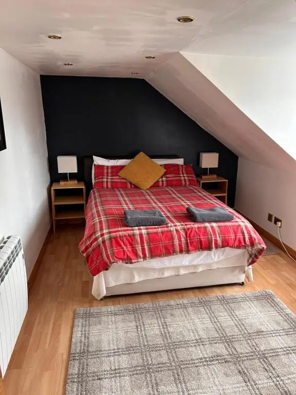 a bedroom with a bed with a red plaid blanket at Telford Road Apartment in Inverness