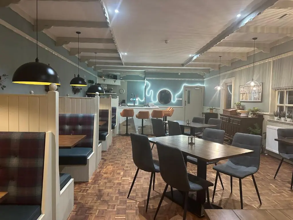 a restaurant with a table and chairs and a kitchen at The 1645 Inn in Nairn