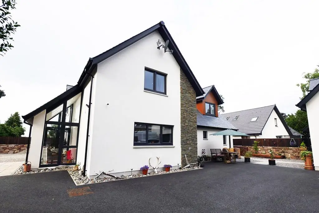a white house with a black roof at Pinewood Cottage Apartment & B&B Inverness in Inverness