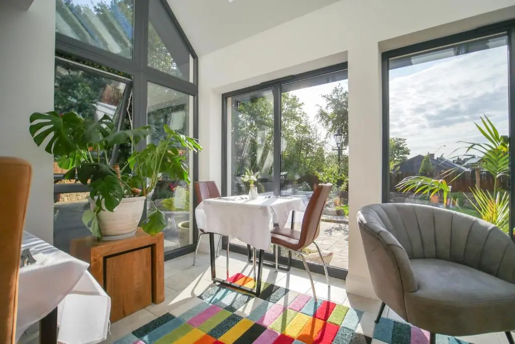 a dining room with a table and chairs and windows at Pinewood Cottage Apartment & B&B Inverness in Inverness
