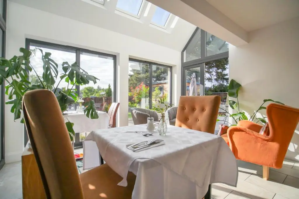 a dining room with a table and chairs and windows at Pinewood Cottage Apartment & B&B Inverness in Inverness