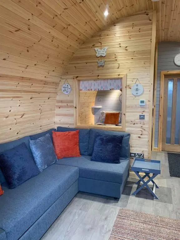 a blue couch in a room with wooden walls at Daviot Luxury Pods in Inverness
