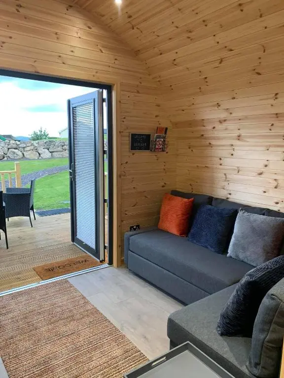 a living room with a couch and a sliding glass door at Daviot Luxury Pods in Inverness