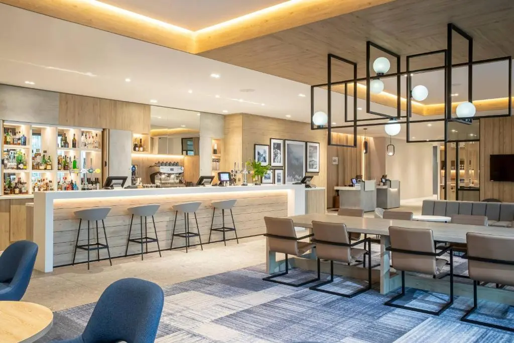a lobby with a table and chairs and a bar at Courtyard by Marriott Inverness Airport in Inverness