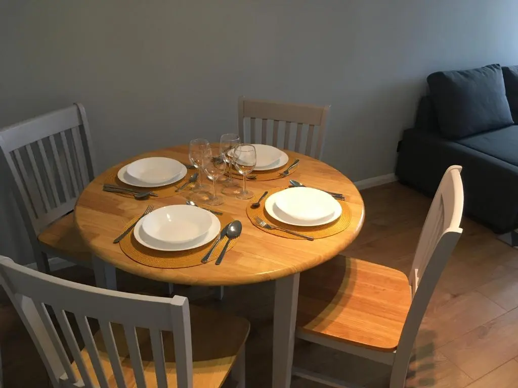 a wooden table with plates and wine glasses on it at Highfield apartment in Inverness