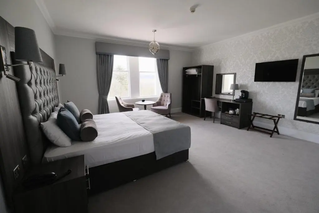 a hotel room with a large bed and a desk at Fife Lodge Hotel in Banff